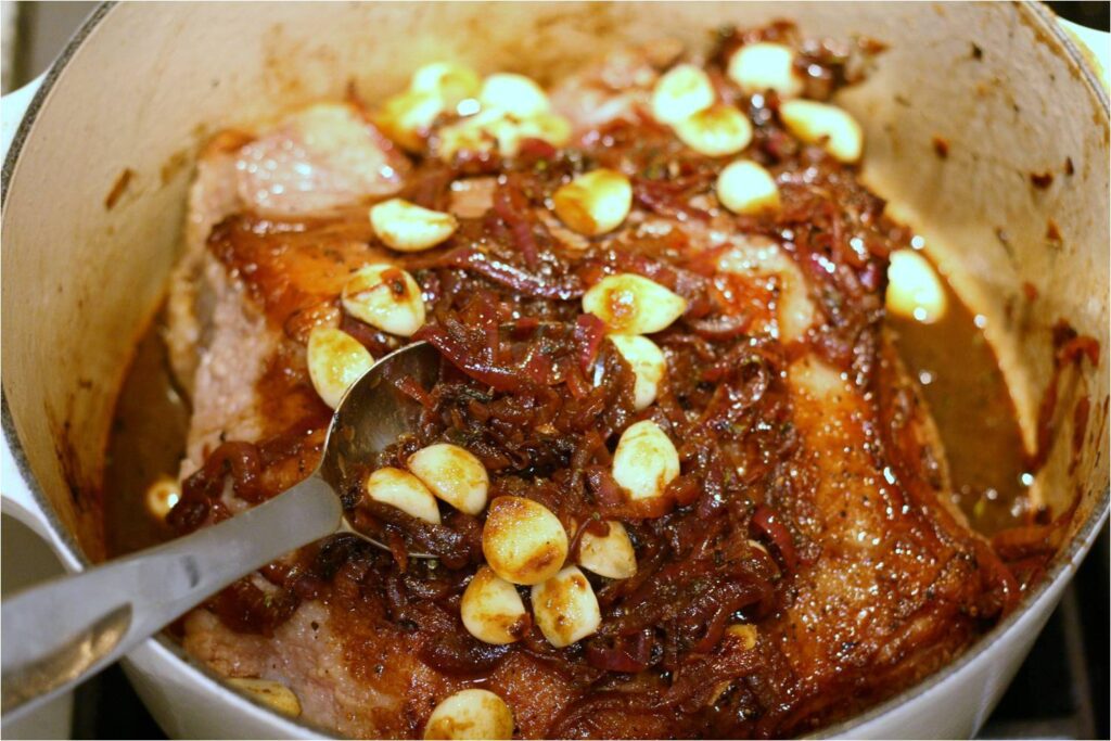 Spoon onions and garlic cloves over brisket